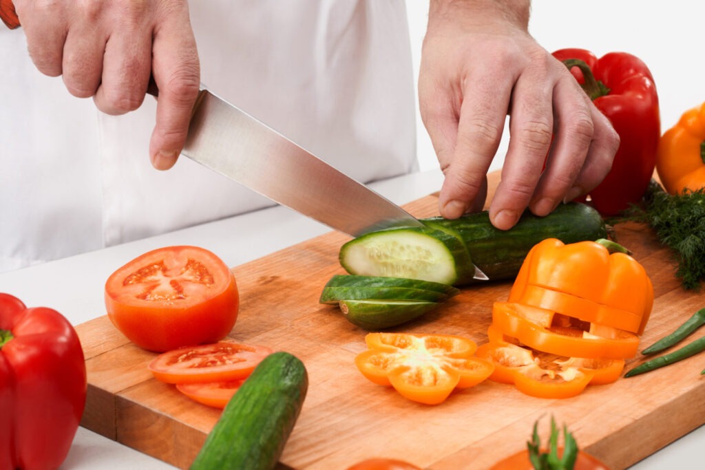 Cutting cucumbers › 스타일리쉬 플레이스 신선한 채소와 과일을 다듬고 있는 손과 나무 도마의 모습.