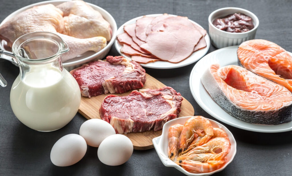 Protein diet raw products on the wooden background › 스타일리쉬 플레이스 다양한 채소와 곡물, 그리고 일부 육류와 해산물이 함께 놓인 테이블의 모습. 플렉시테리언이 채식 위주로 식사를 하면서도 선택적으로 육류를 포함하는 식습관을 강조하는 이미지.