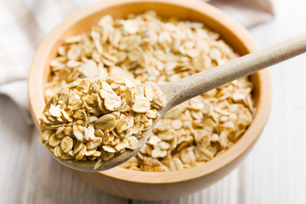 oat flakes on a wooden spoon › 스타일리쉬 플레이스 나무 숟가락에 담긴 오트밀과 나무 그릇에 가득 담긴 오트밀의 모습. 채식주의자의 건강한 아침 식사를 강조하는 이미지.
