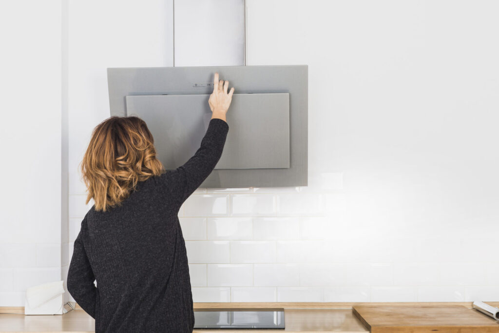 female opening kitchen hoods › 스타일리쉬 플레이스 주방 후드를 열고 필터를 점검하는 모습, 주방 후드 청소 주기 및 유지 관리를 보여준다.
