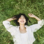 자연 속에서 스트레스 해소를 위해 누워 있는 여성이 웃고 있는 모습