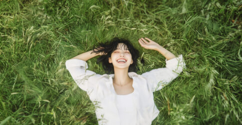 자연 속에서 스트레스 해소를 위해 누워 있는 여성이 웃고 있는 모습