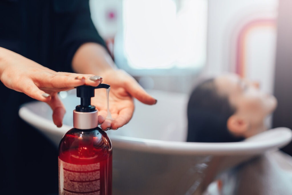 Hairdresser washes customer hair with shampoo › 스타일리쉬 플레이스 헤어살롱에서 샴푸를 손에 덜어내고 부시시한 머릿결 관리에 집중하는 장면