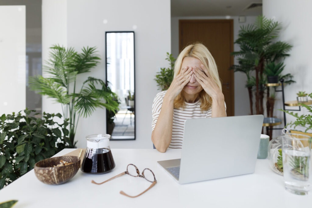 Tired freelancer rubbing eyes sitting at desk in home › 스타일리쉬 플레이스 책상 앞에서 눈을 감고 스트레스를 해소하려는 여성, 시간 관리와 워라밸의 중요성을 상징하는 이미지