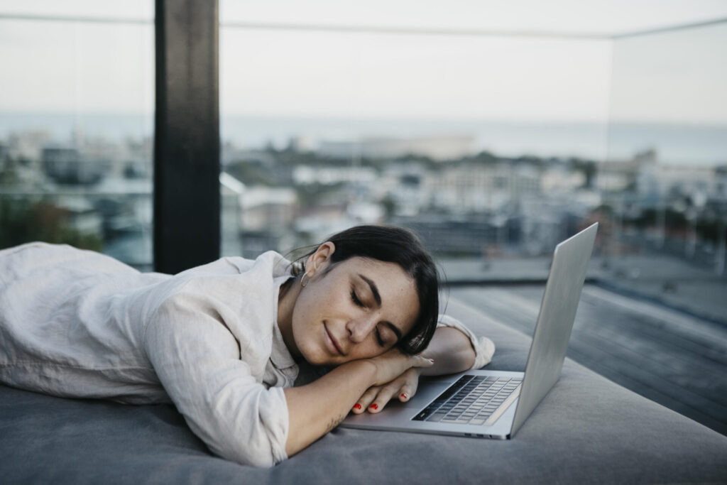Tired freelancer resting on couch by laptop › 스타일리쉬 플레이스 노트북 옆에서 휴식을 취하며 잠든 여성, 시간 관리와 균형 잡힌 라이프스타일의 중요성을 상징