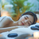 조명이 은은한 스파 환경에서 마사지 돌과 수건을 이용해 편안하게 누워 있는 여성