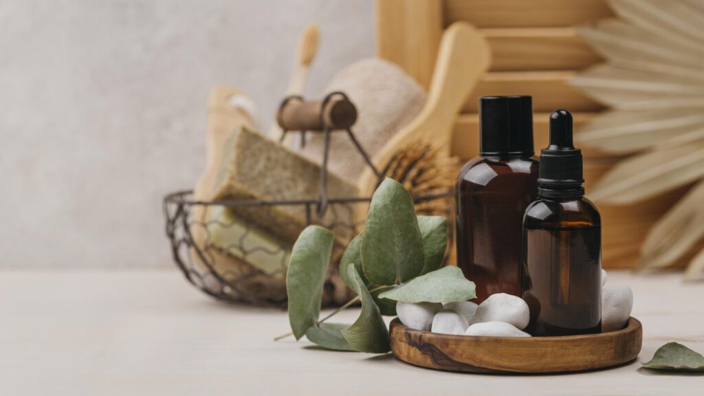 organic body oil front view High quality photo › 스타일리쉬 플레이스 스파 오일 병과 나뭇잎, 돌이 놓인 트레이 옆에 천연 스크럽 브러쉬와 바디 케어 용품이 담긴 철제 바구니