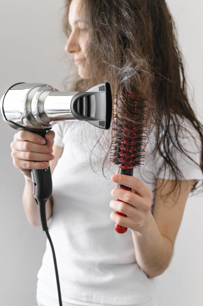young female drying hair › 스타일리쉬 플레이스 헤어브러시와 드라이어로 부시시한 머리카락을 관리하는 여성