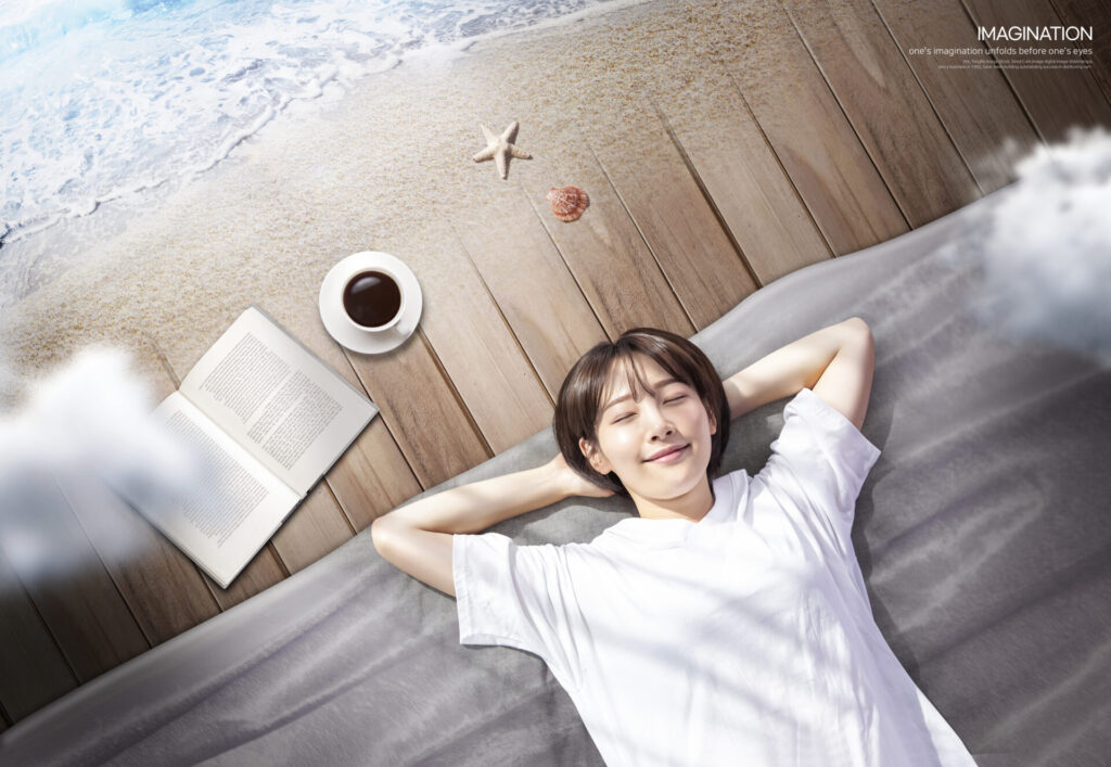 CK_ti436a35610 › 스타일리쉬 플레이스 해변가를 배경으로 데크 위에 누워 여유를 즐기는 여성과 커피, 책이 놓인 장면