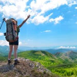 산 정상에서 배낭을 멘 채 성취감을 만끽하는 사람