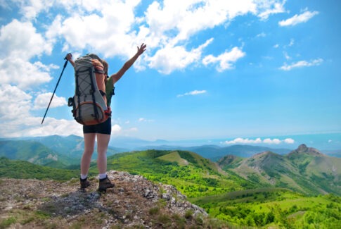 산 정상에서 배낭을 멘 채 성취감을 만끽하는 사람