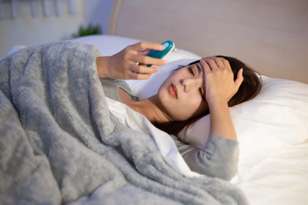 woman sick and has fever › 스타일리쉬 플레이스 침대에 누워 이마에 손을 올린 채 체온계를 확인하는 여성, 환절기 감기에 대비하는 모습