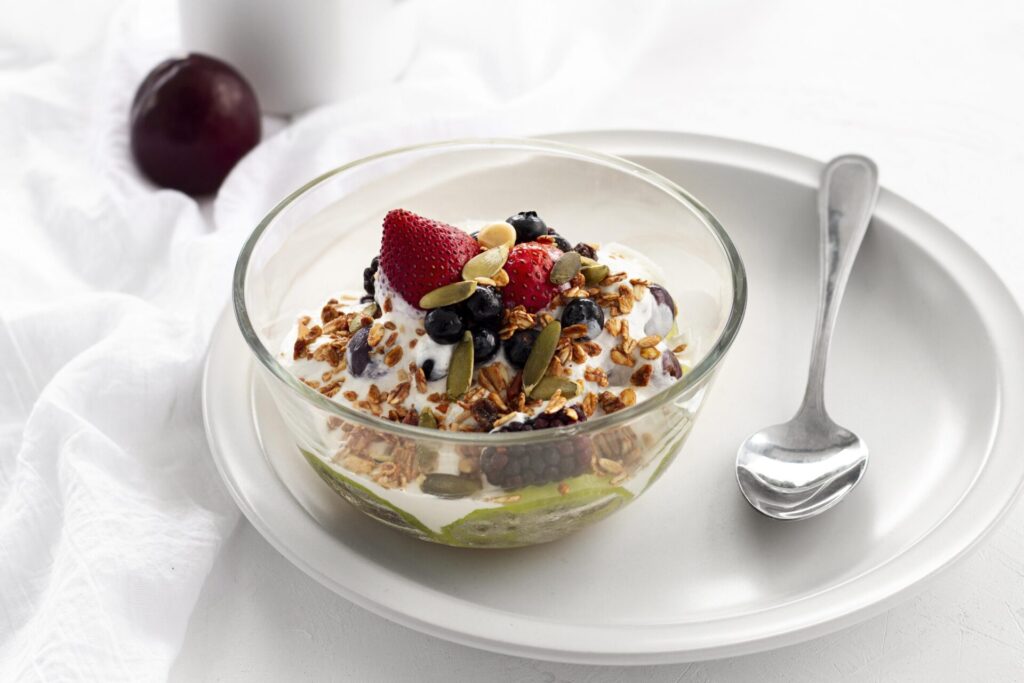 high angle yogurt with cereals fruits › 스타일리쉬 플레이스 면역력 강화를 위한 아침 식사로, 베이글·계란·사과·단호박·채소 등 건강 재료가 준비된 식탁 사진