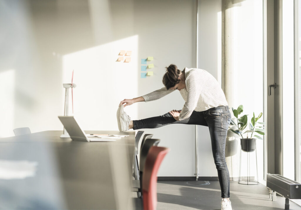 Businesswoman stretching in office › 스타일리쉬 플레이스 사무실 탁자에 다리를 올려 스트레칭하며 재택근무 중 건강을 챙기는 여성