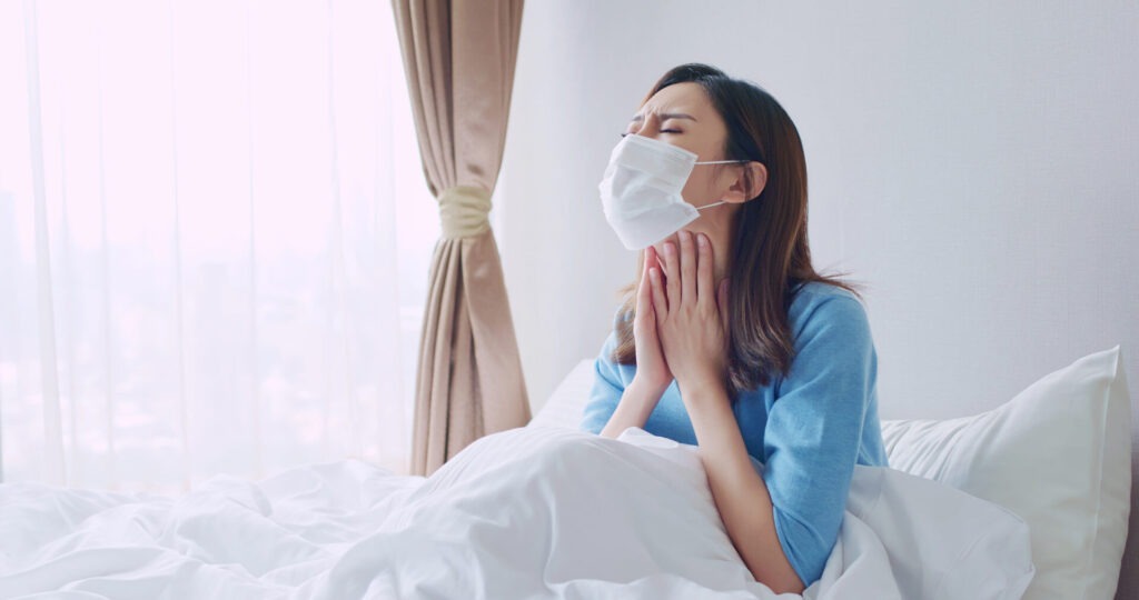 asian woman cough in bedroom › 스타일리쉬 플레이스 마스크를 쓰고 침대에 앉아 목이 아파 고생하는 여성