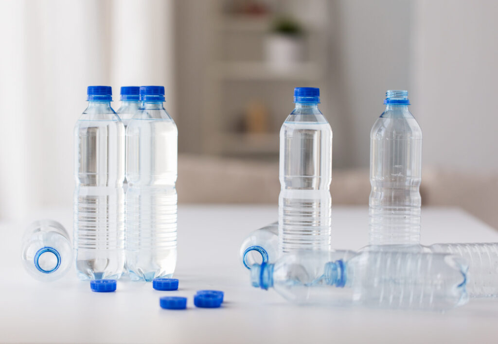 close up of bottles with drinking water on table › 스타일리쉬 플레이스 환경보호를 위해 재활용이 필요한 파란 뚜껑 일회용 생수병 여러 개가 테이블 위에 놓여 있는 모습
