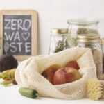 환경보호를 위한 플라스틱 ZERO 장보기: 망사 에코백에 사과를 담고 유리병·대나무 솔을 배치한 모습