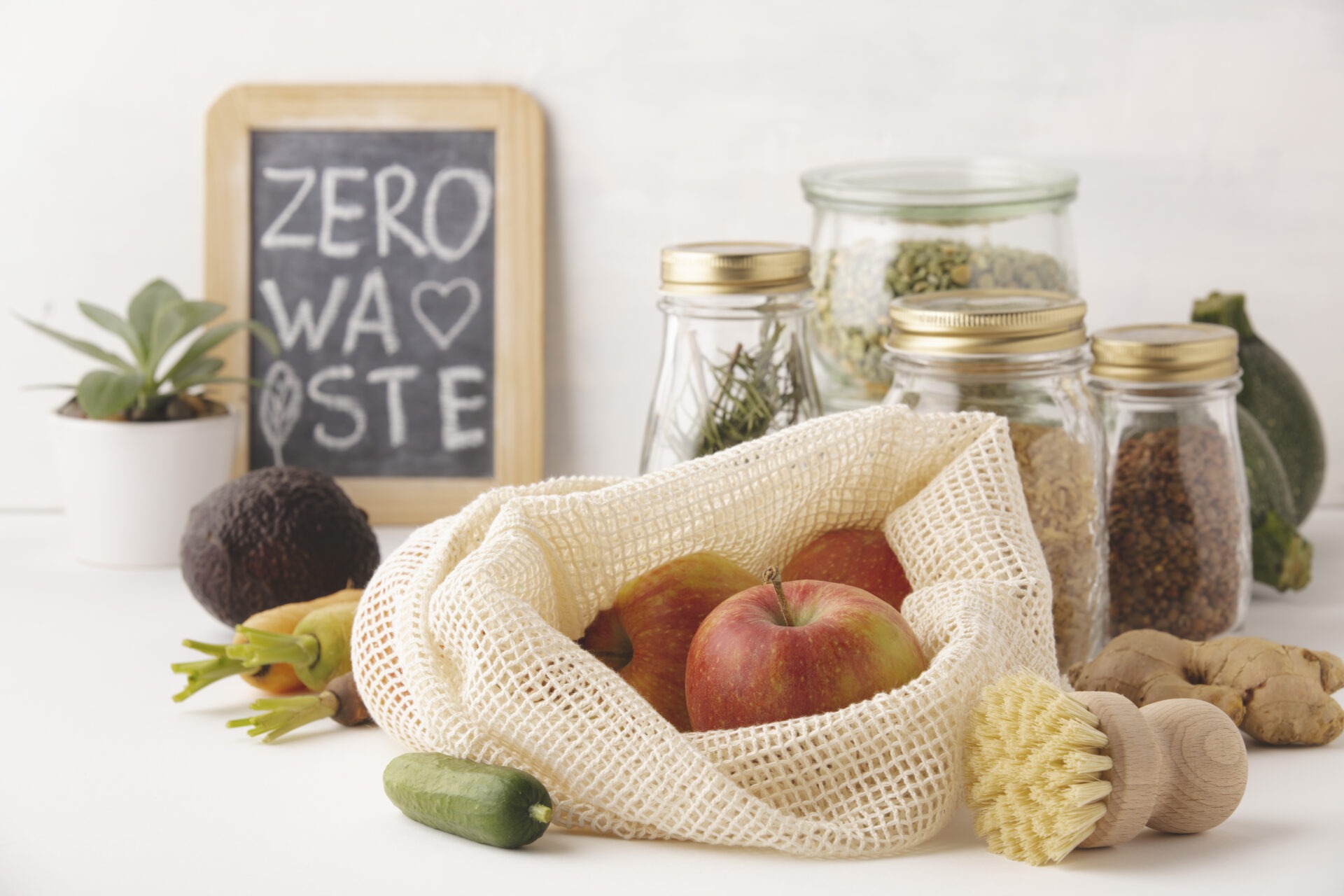 환경보호를 위한 플라스틱 ZERO 장보기: 망사 에코백에 사과를 담고 유리병·대나무 솔을 배치한 모습