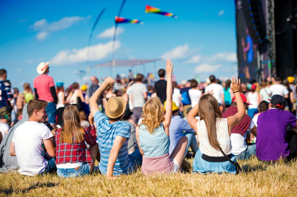 Teenagers summer music festival sitting in front of stage › 스타일리쉬 플레이스 잔디밭에 앉아 여름축제 공연을 관람하는 사람들, 무대 앞에서 손을 흔들며 즐기는 관중들