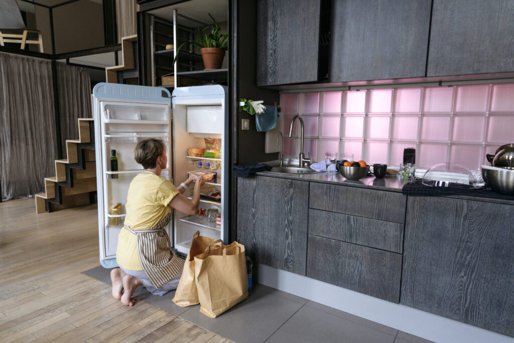 Woman stocking groceries in fridge at home › 스타일리쉬 플레이스 냉장고 정리하는 미니멀리스트 여성의 주방 일상, 식재료 정돈 중