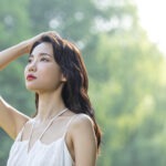 햇볕 아래 두피를 손으로 감싸며 민감 두피를 진정시키는 여성의 모습