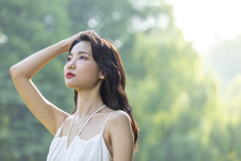 햇볕 아래 두피를 손으로 감싸며 민감 두피를 진정시키는 여성의 모습