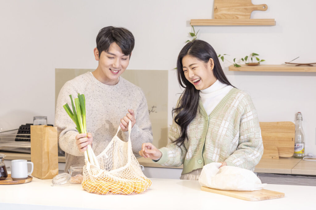 에코백에 담긴 채소를 정리하는 커플, 제로웨이스트 실천을 위한 친환경 장보기와 주방 풍경