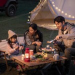 가족이 캠핑장에서 미니 주방템으로 요리를 즐기는 모습, 감성적인 조명과 주방템 세팅