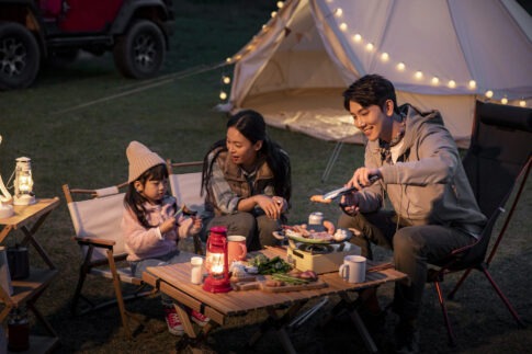 가족이 캠핑장에서 미니 주방템으로 요리를 즐기는 모습, 감성적인 조명과 주방템 세팅